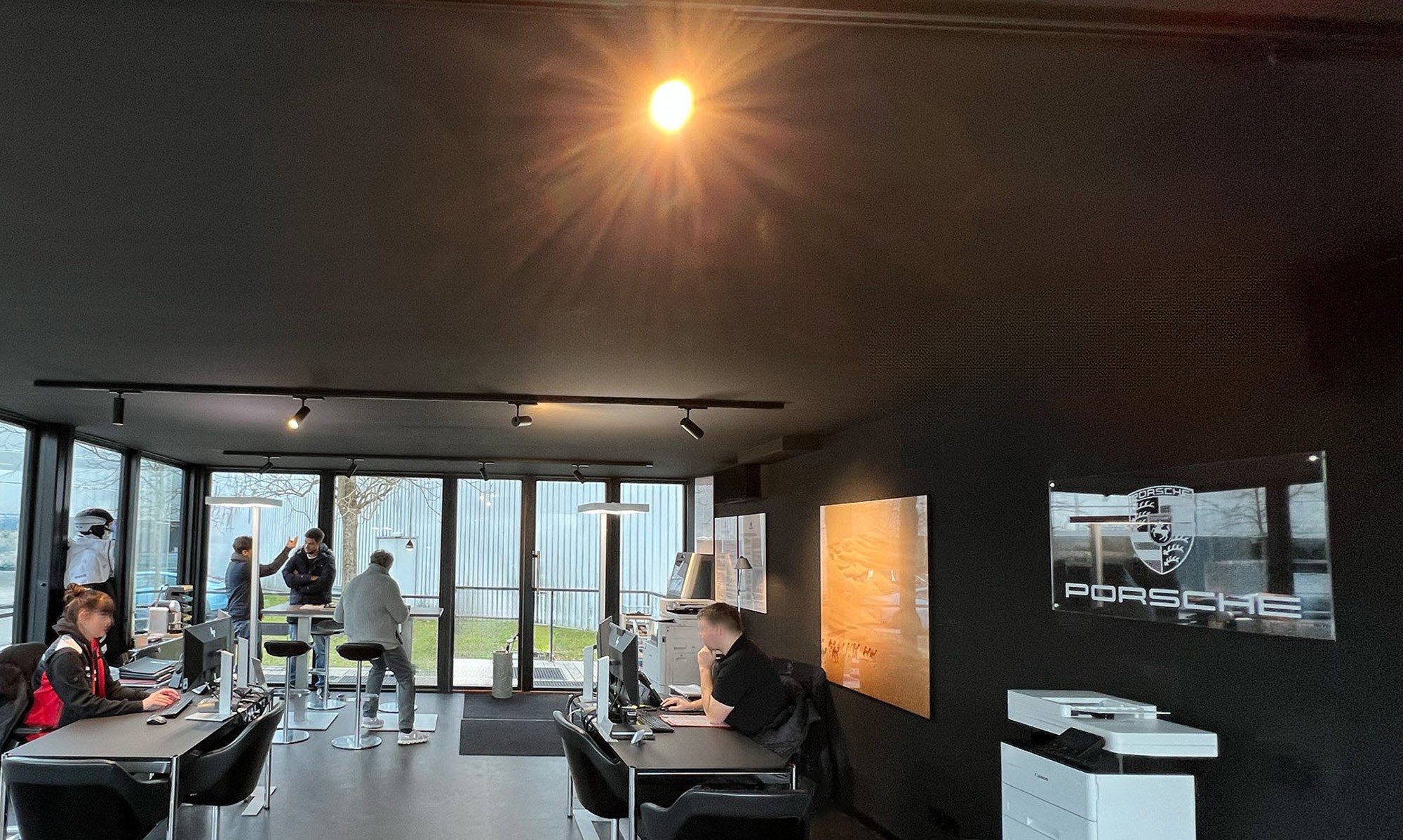 Aufnahme zur Ausstattung für Gewerbe: Innenraum eines KOYA Moduls im Porsche Zentrum Aargau mit Schreibtischen und Hochtischen vor der Glasfront