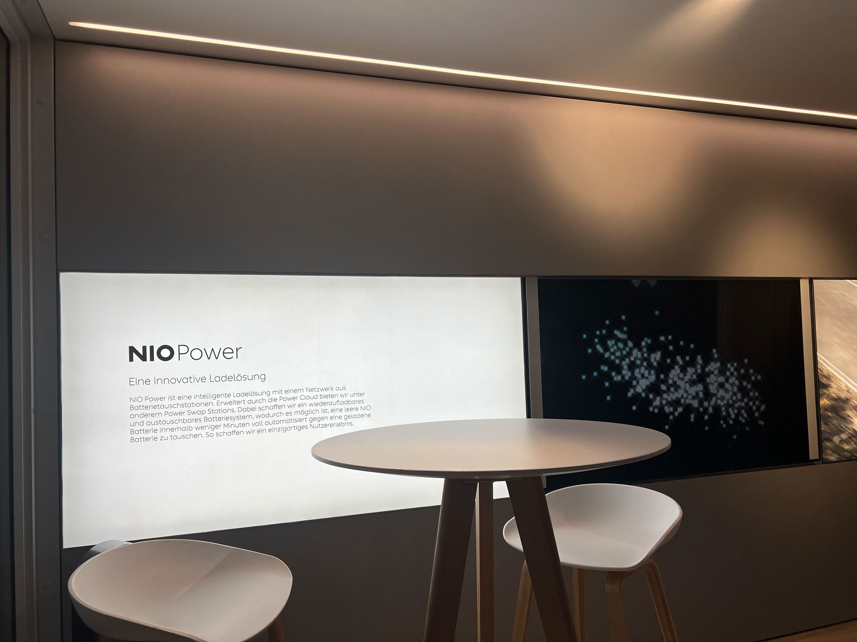 Hochtisch mit Hockern vor einer Wand mit Holzlamellen im KOYA Roadshow-Modul