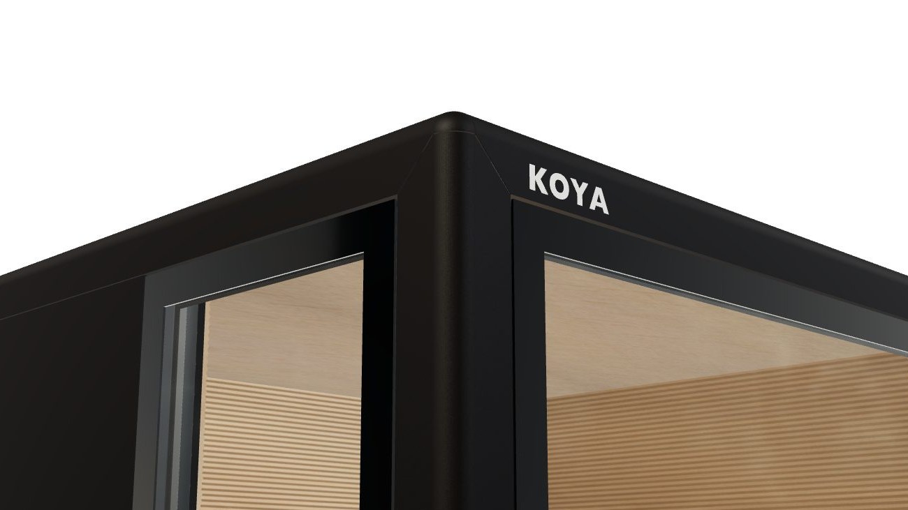 Obere Ecke des Sauna Cube in mattem Tiefschwarz mit weißem KOYA-Schriftzug, hinter dem Glas die Holzwand