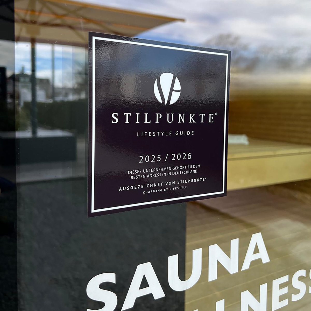 Plakette des Stilpunkte Lifestyle Guide an der Glasfront der Sauna