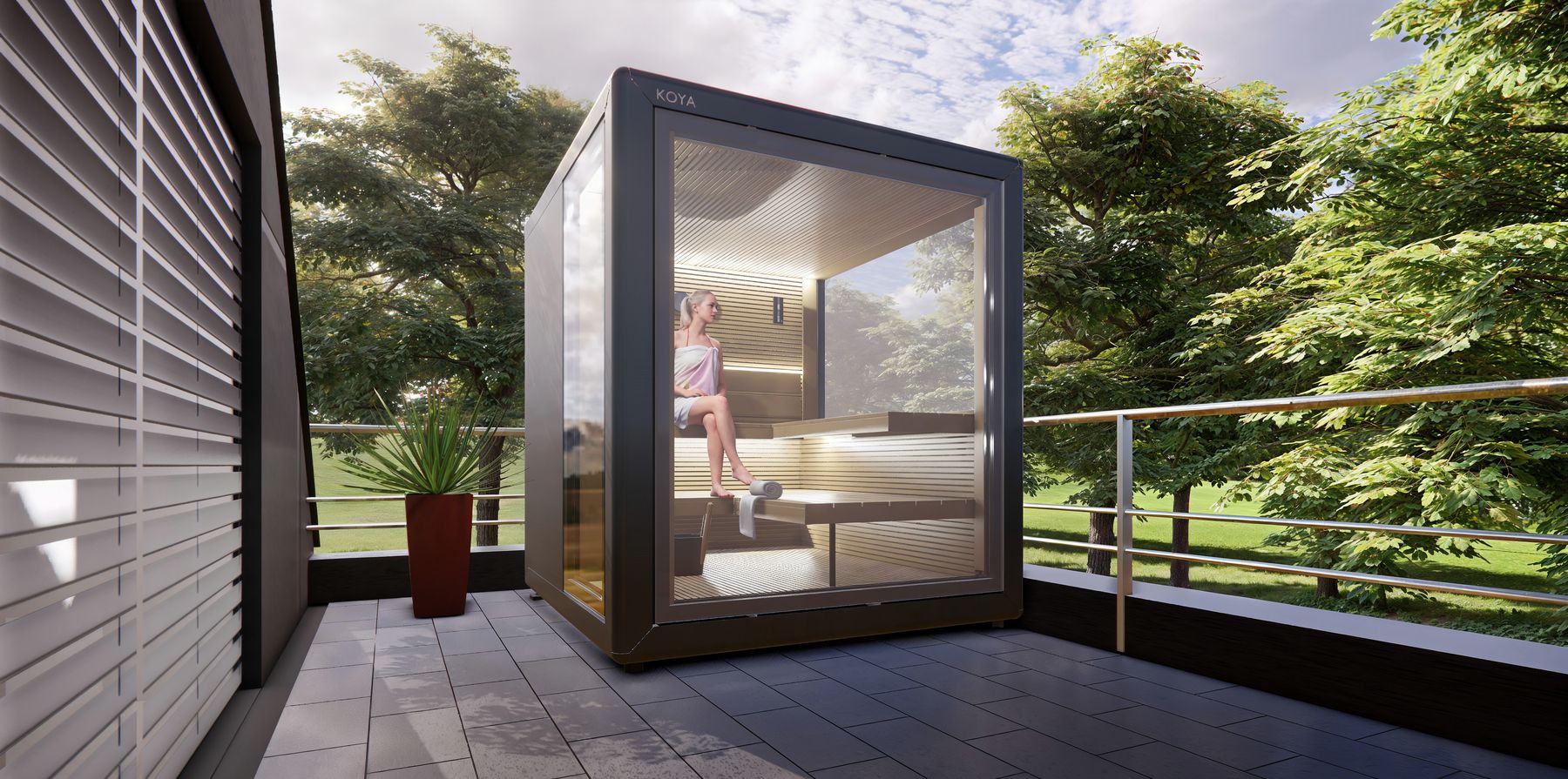 Sauna Cube mit Glasfront und KOYA-Schriftzug auf einer Terrasse mit Geländer, innen eine Frau auf der Bank