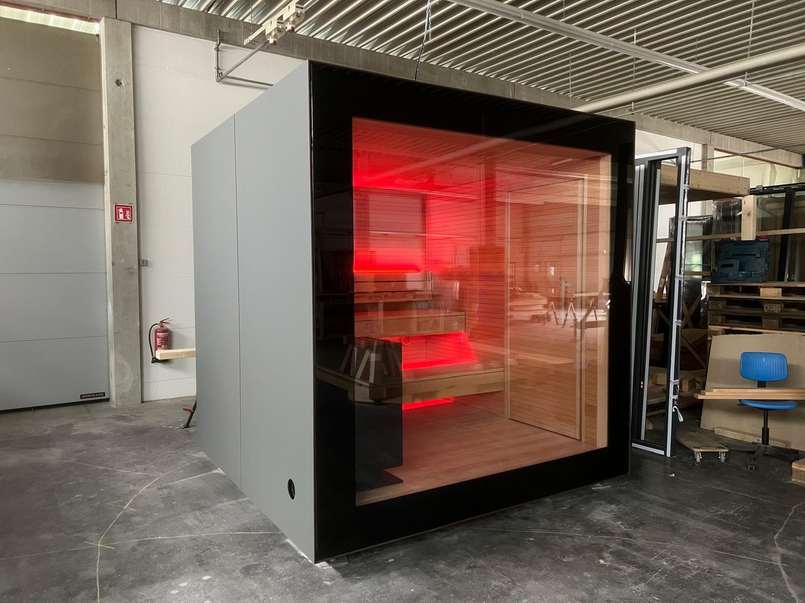 Aufnahme: KOYA Studio Ganzglas mit hellgrauer Fassade in der Werkhalle, innen rot beleuchtet